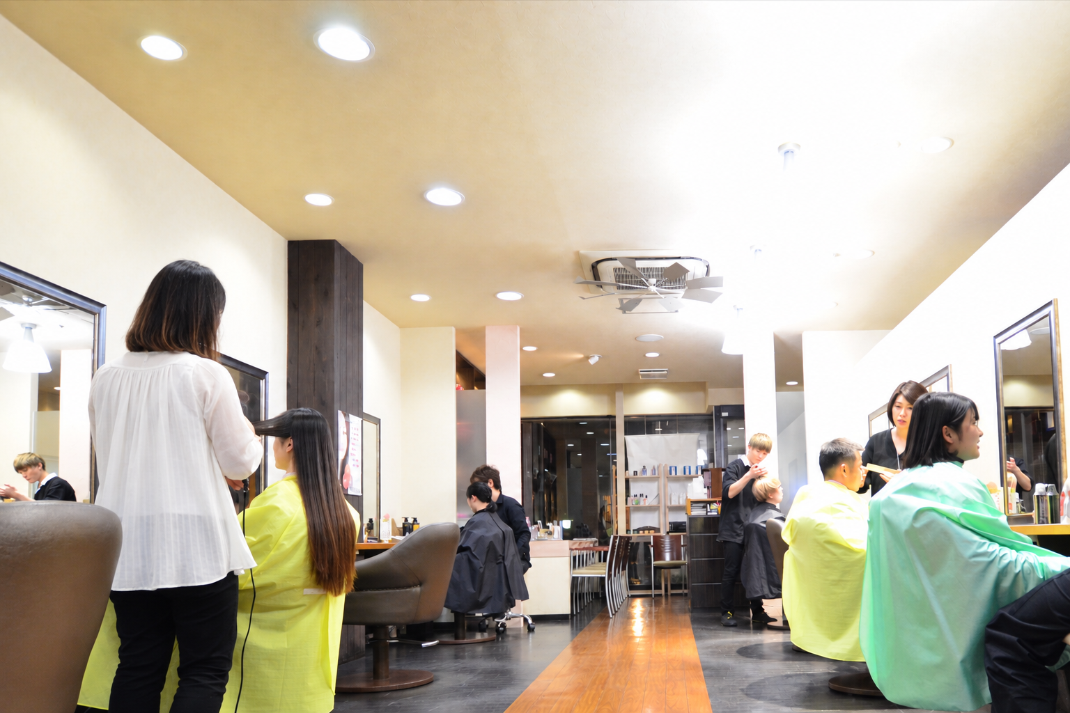 明るい店内でスタイリストが施術しているMomomaruJapanのサロン風景